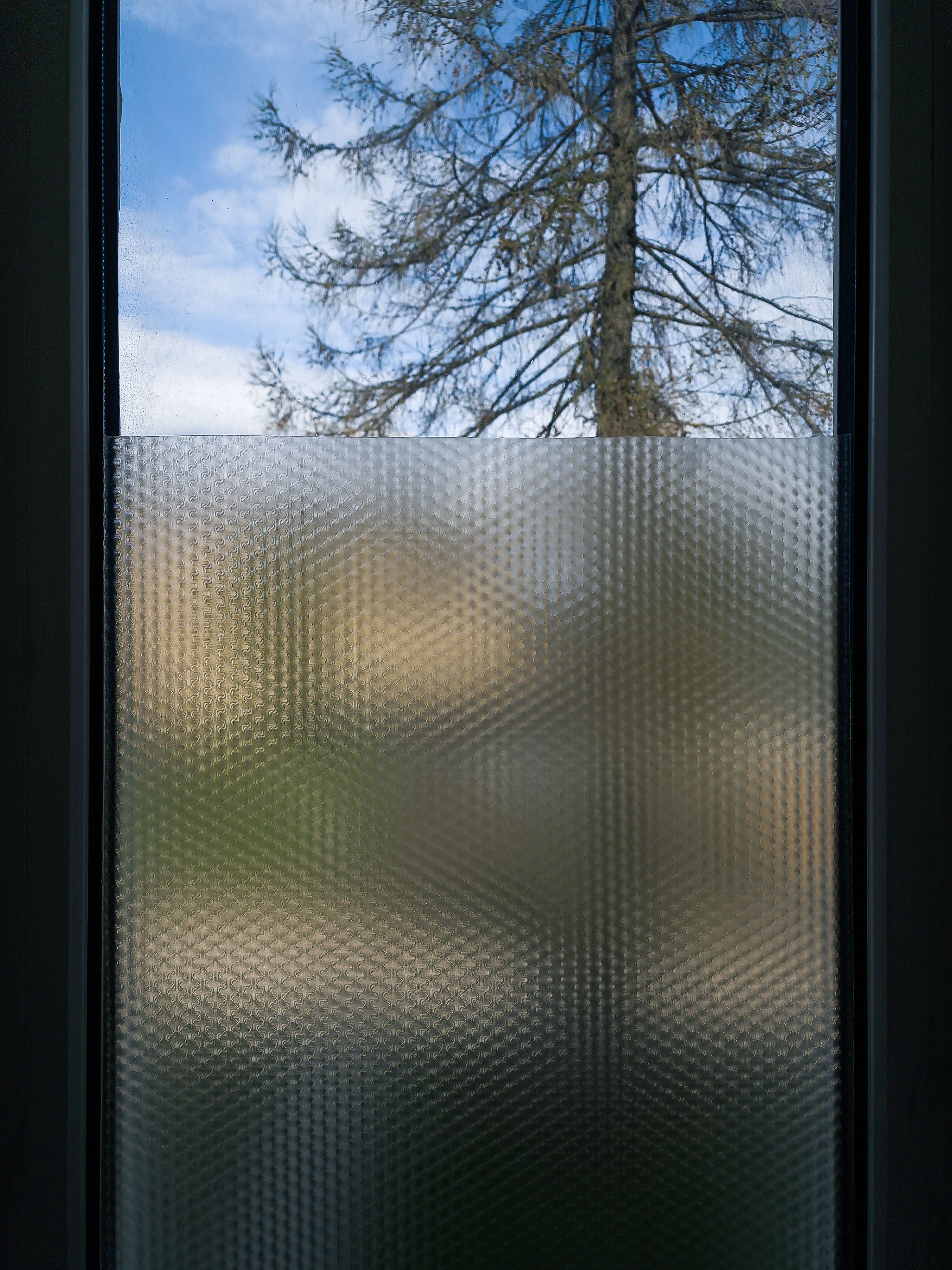 Toilet's window glass with film sticker for reduced visibility across.