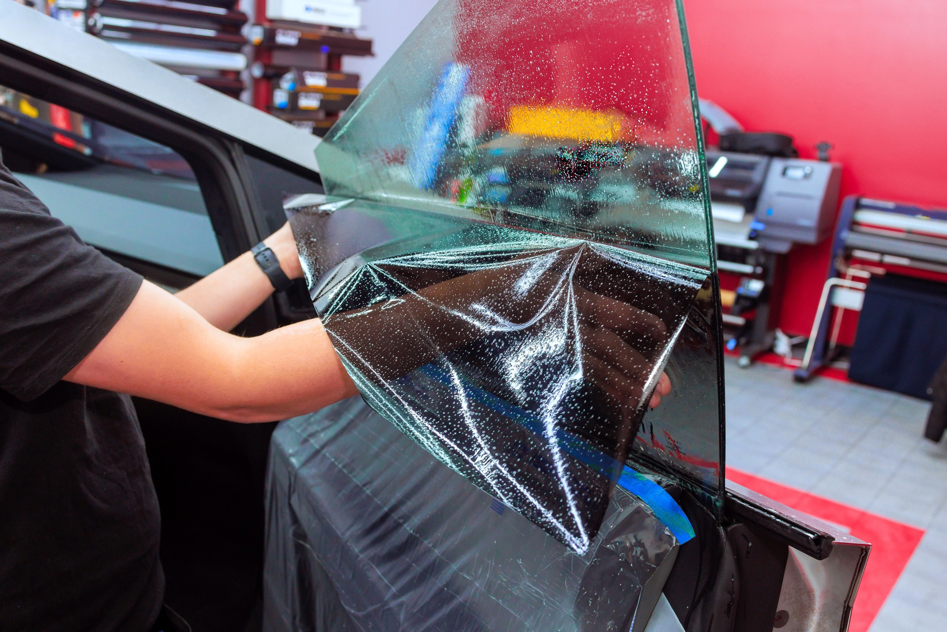 Professional window tinting process in a workshop using high quality film for vehicle enhancement project